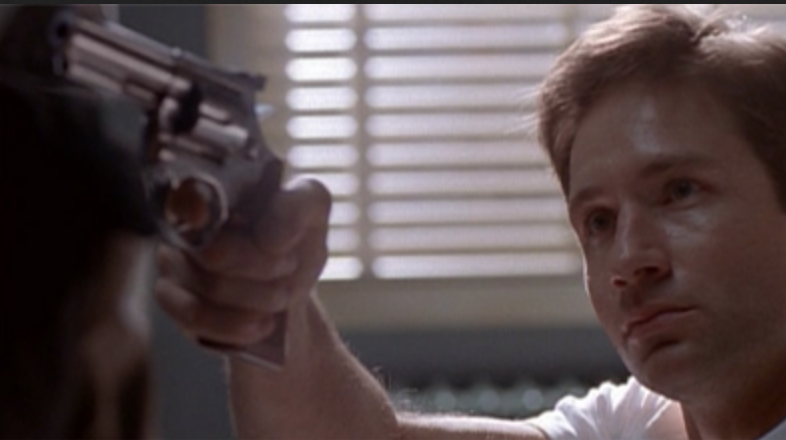 Agent Mulder aiming a revolver somewhere off screen