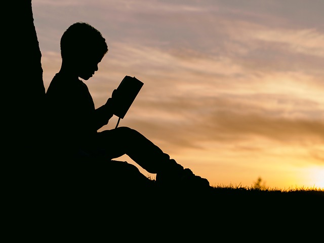 silhouette image of child reading